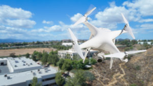 Unmanned Aircraft System (UAV) Quadcopter Drone In The Air Over Commercial Buildings. emerging technology on commercial real estate